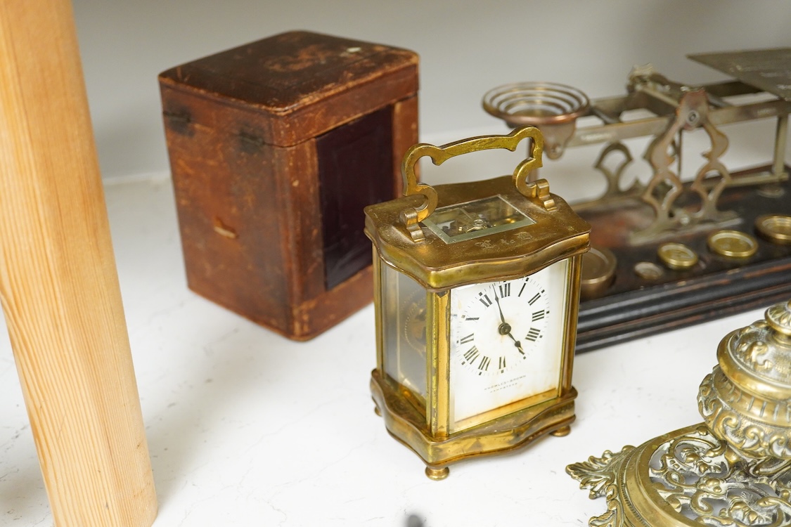 A collection of items to include a leather cased gilt brass French carriage clock, a German bronze Jugendstil inkwell, a late 19th century ink brass inkwell, a set of postal scales with weights, a Temple & Crook small co